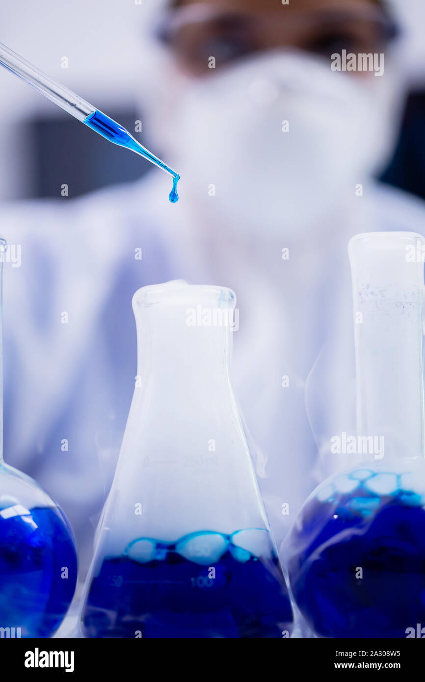 In der Nähe der weiblichen Wissenschaftler mit blauen Lösung fallen von der Pipette in einem modernen Labor. Stockfoto
