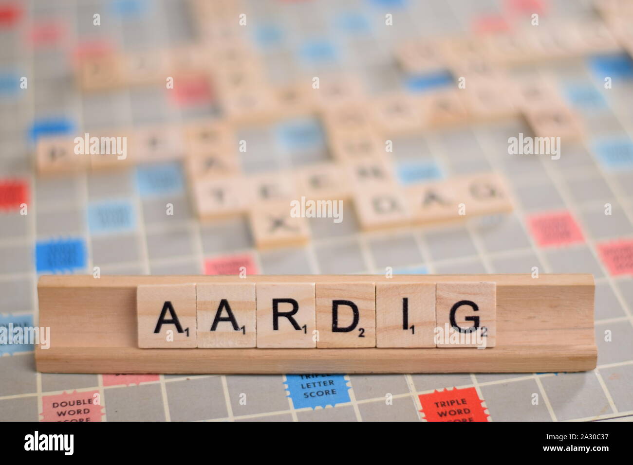 Das niederländische Wort "Aardig" (auf Deutsch: 'nice') in Holz- Scrabble Fliesen auf einem Baugruppenträger. Der Hintergrund ein Vintage board, unscharf, mit Kopie Raum Stockfoto