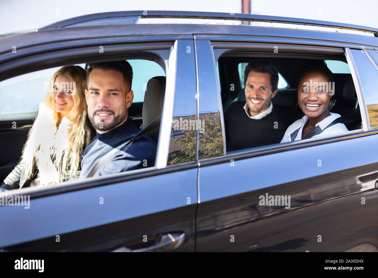 Gruppe von lächelnden Freunde in dem Auto auf der Straße Reise zusammen, die sich aus dem Fenster Stockfoto