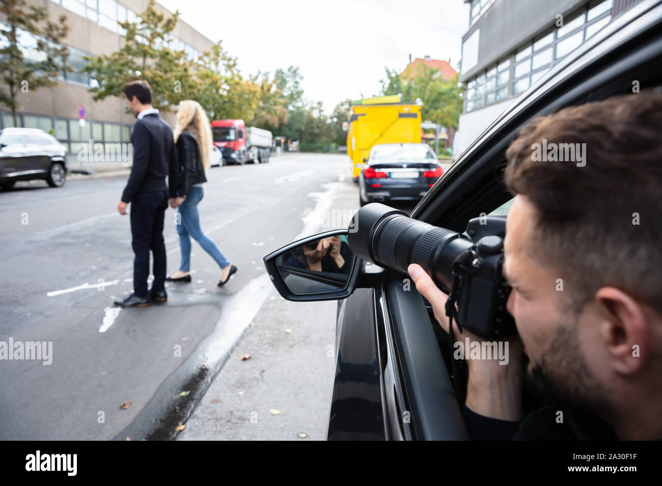 Junge männliche Spy Sitzen im Auto, Foto von einem Paar zu Fuß auf der Straße Stockfoto