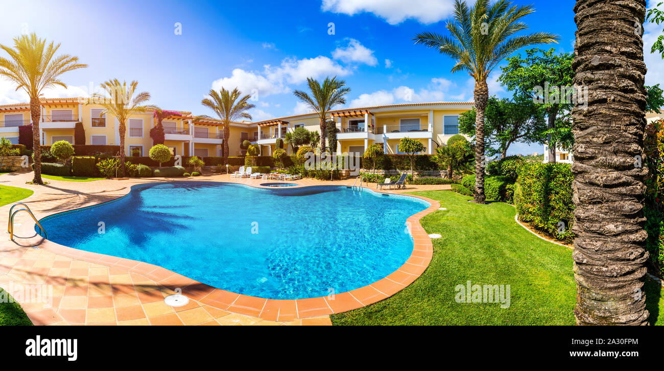 Swimmingpool, Liegestühle und Palmen bei einem warmen sonnigen Tag, paradise Ziel für Ferien. Hinterhof Schwimmbad mit Garten voller Pal Stockfoto