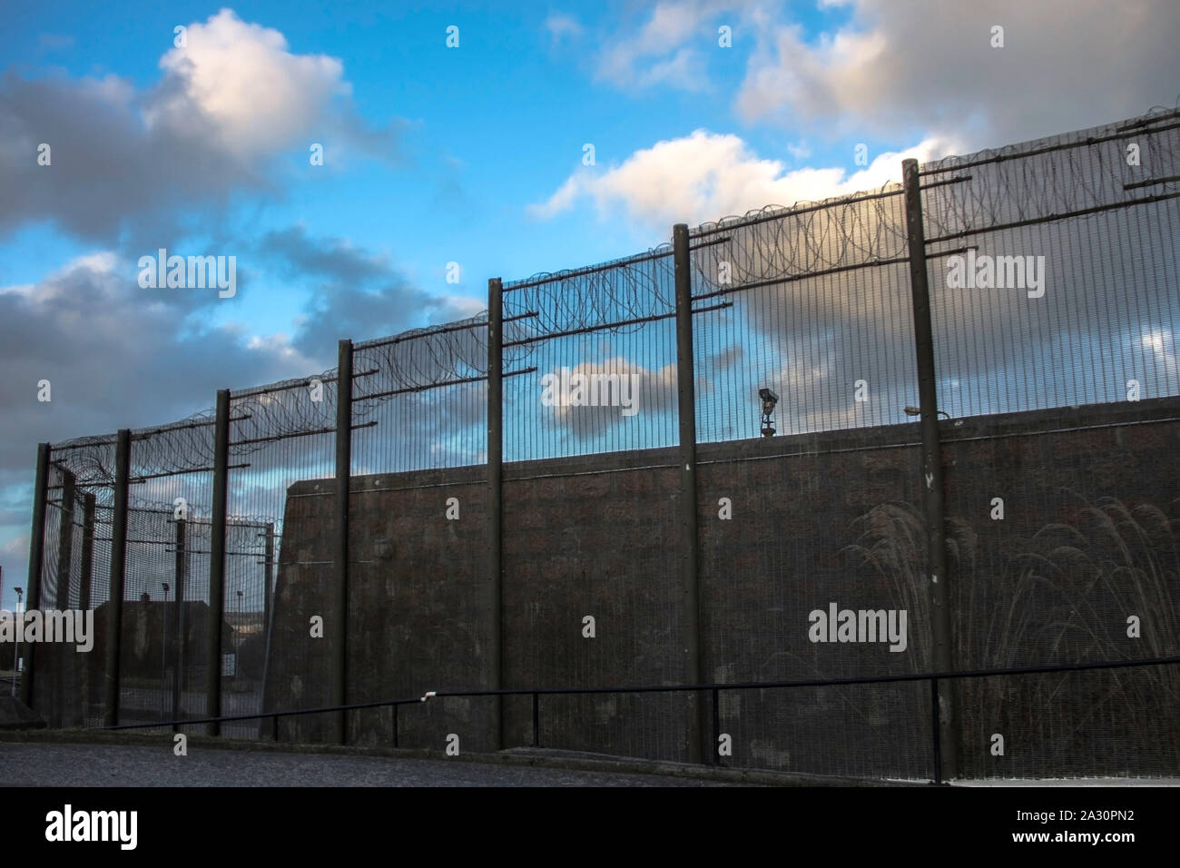 Gefängnismauern und einen Zaun mit Spikes auf dem Hintergrund des blauen Himmels. Peterhead Gefängnis Museum, Aberdeenshire, Schottland, Vereinigtes Königreich. Stockfoto