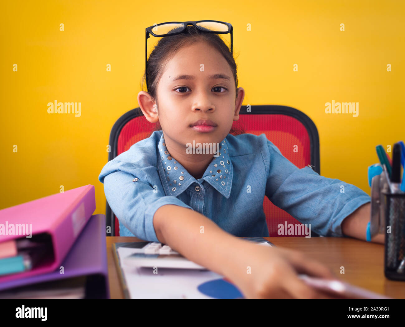 Süße Mädchen Arbeiten am Schreibtisch mit Dokument isoliert gelben Hintergrund. Konzept der Leistung. Stockfoto