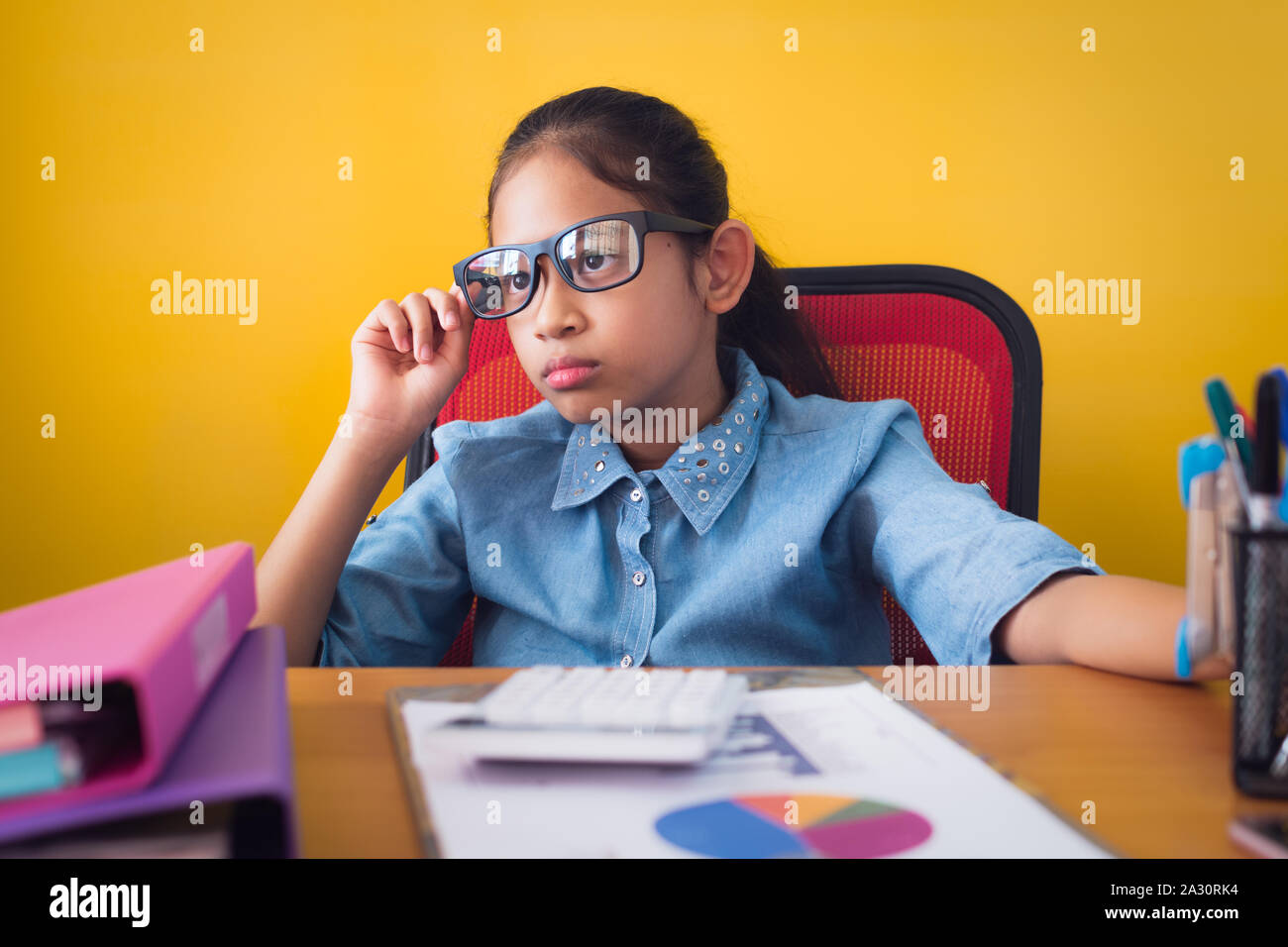 Nettes Mädchen mit Brille mit der Idee von der Planung die Arbeiten am Schreibtisch mit Dokument isoliert gelben Hintergrund, Bildung Konzept. Stockfoto