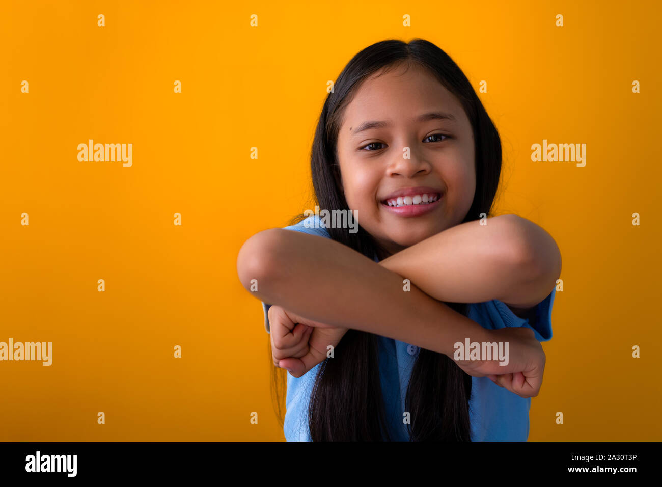 Lächelnd asiatische Mädchen Porträt auf gelbem Hintergrund. Leger gekleidet glückliches Mädchen mit langem Haar Stockfoto