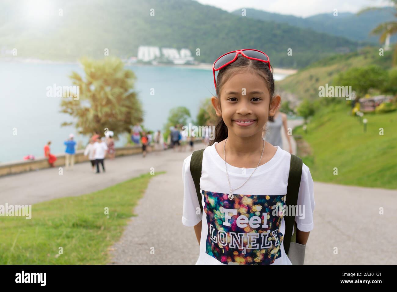 Nettes Mädchen mit Rucksack an Promthep Cape mit Masse von Touristen unter Sonnenlicht in Phuket. Stockfoto
