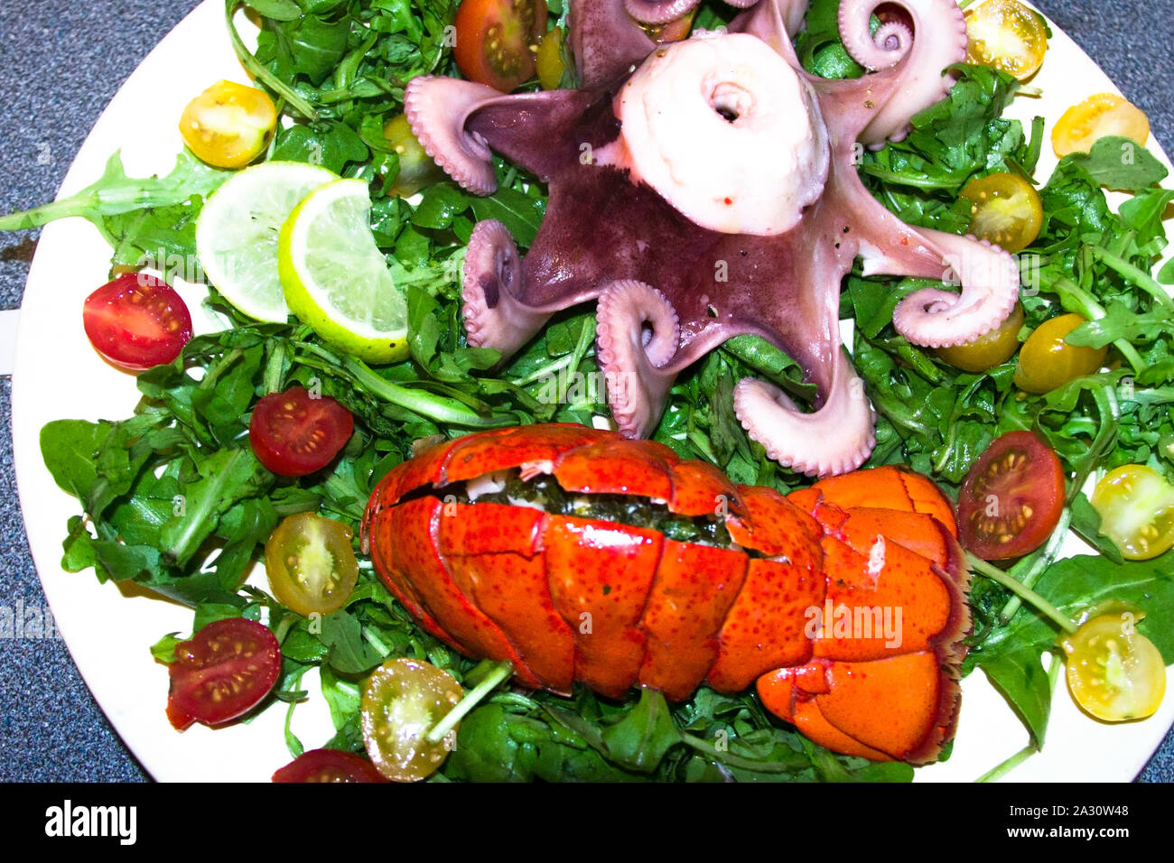 Gekochten Tintenfisch und Hummerschwanz mit Salat auf einen Teller. Sea Food Gericht. Stockfoto
