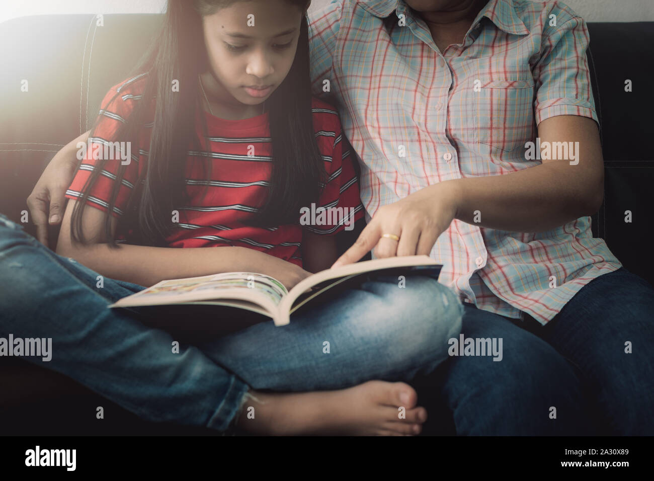 Mutter und Tochter lesen Buch und Spaß haben, während sie die Zeit gemeinsam zu Hause unter der warmen Licht. Stockfoto