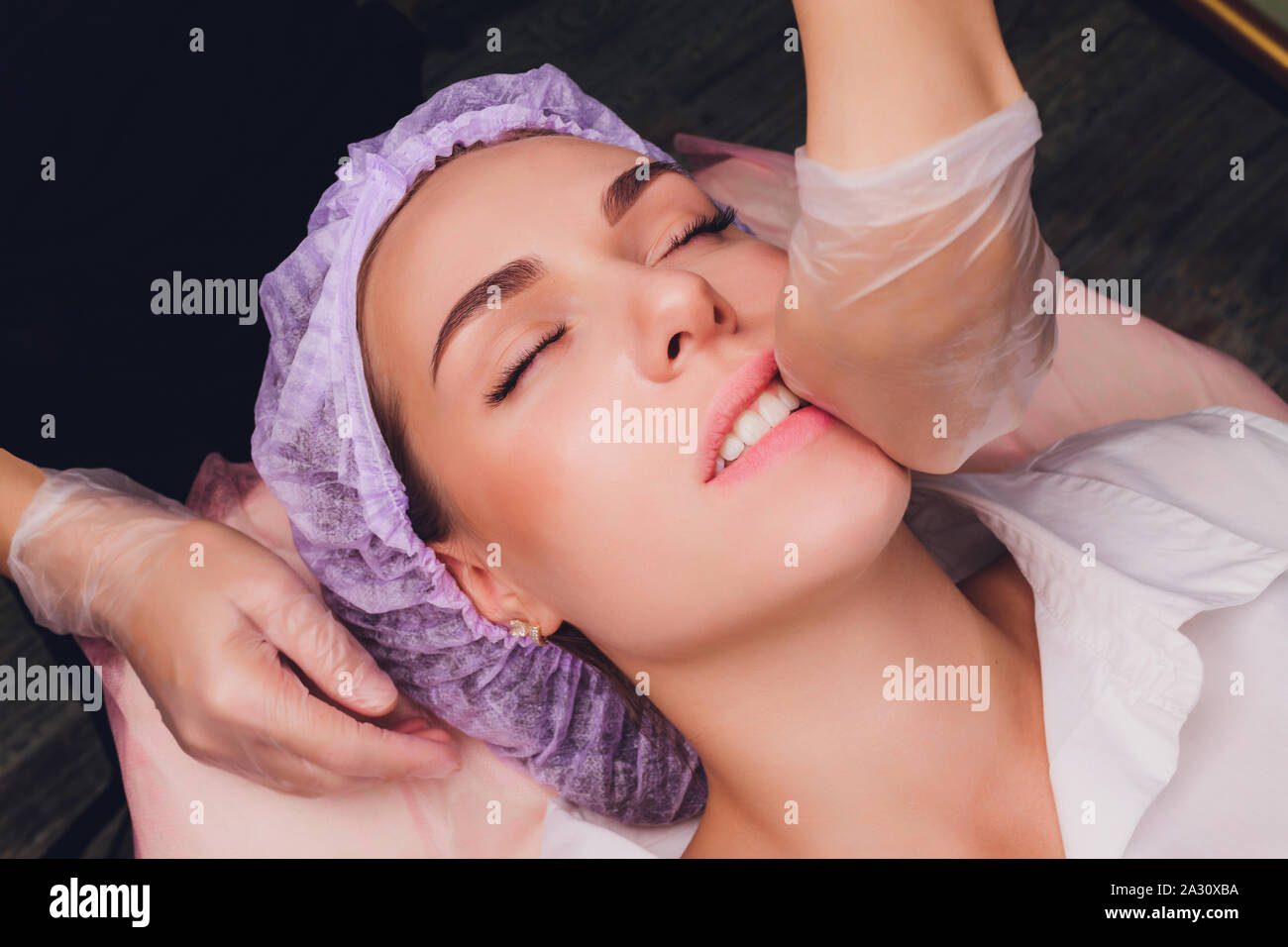 Kosmetiker macht eine bukkale Massage des Gesichts Die Muskeln des Patienten Stockfoto