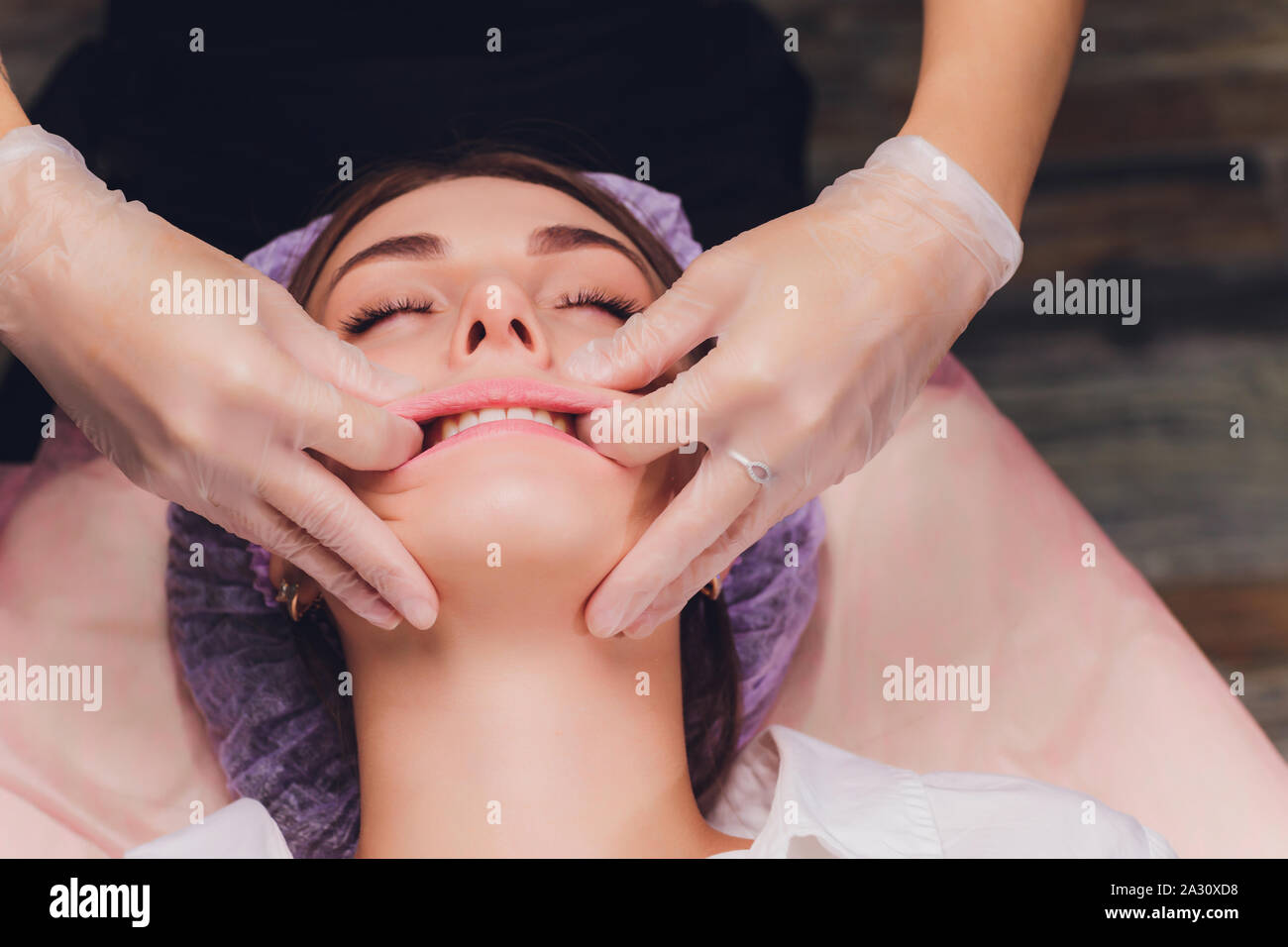 Kosmetiker macht eine bukkale Massage des Gesichts Die Muskeln des Patienten Stockfoto