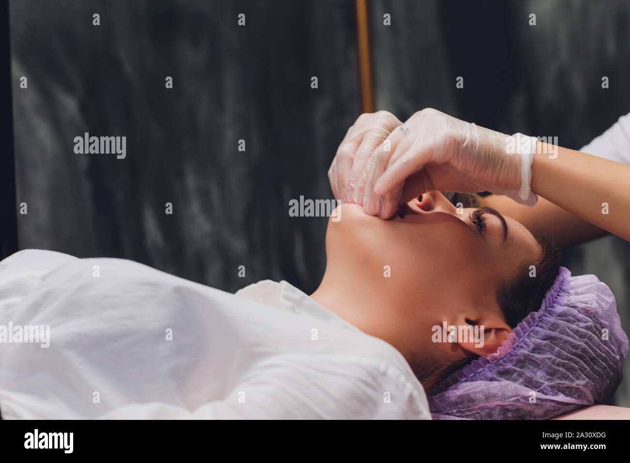 Kosmetiker macht eine bukkale Massage des Gesichts Die Muskeln des Patienten Stockfoto
