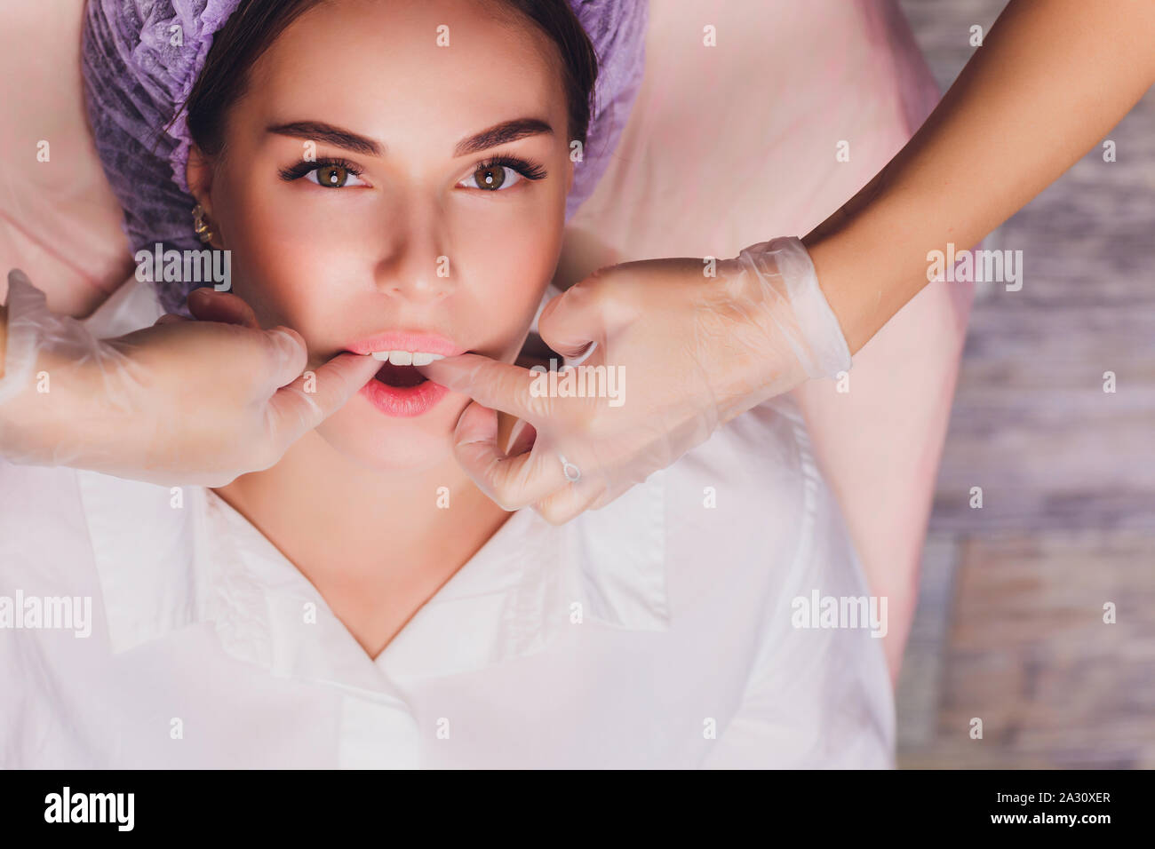 Kosmetiker macht eine bukkale Massage des Gesichts Die Muskeln des Patienten Stockfoto