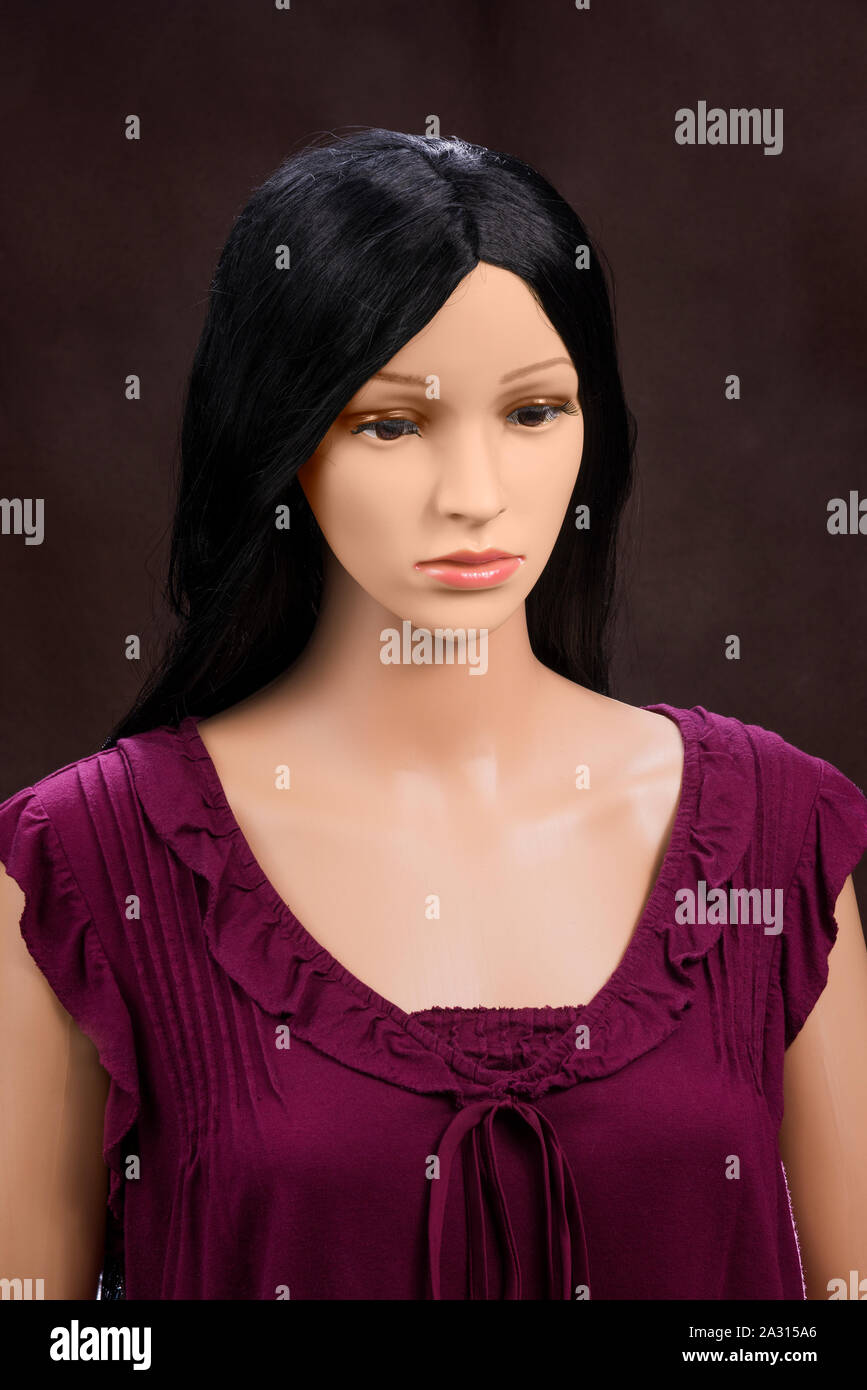 Vertikale Nahaufnahme eines weiblichen Puppe aus der Brust. Sie hat einen ernsten Ausdruck. Sie hat lange schwarze Haare und einen lila Bluse. Braun bac Stockfoto