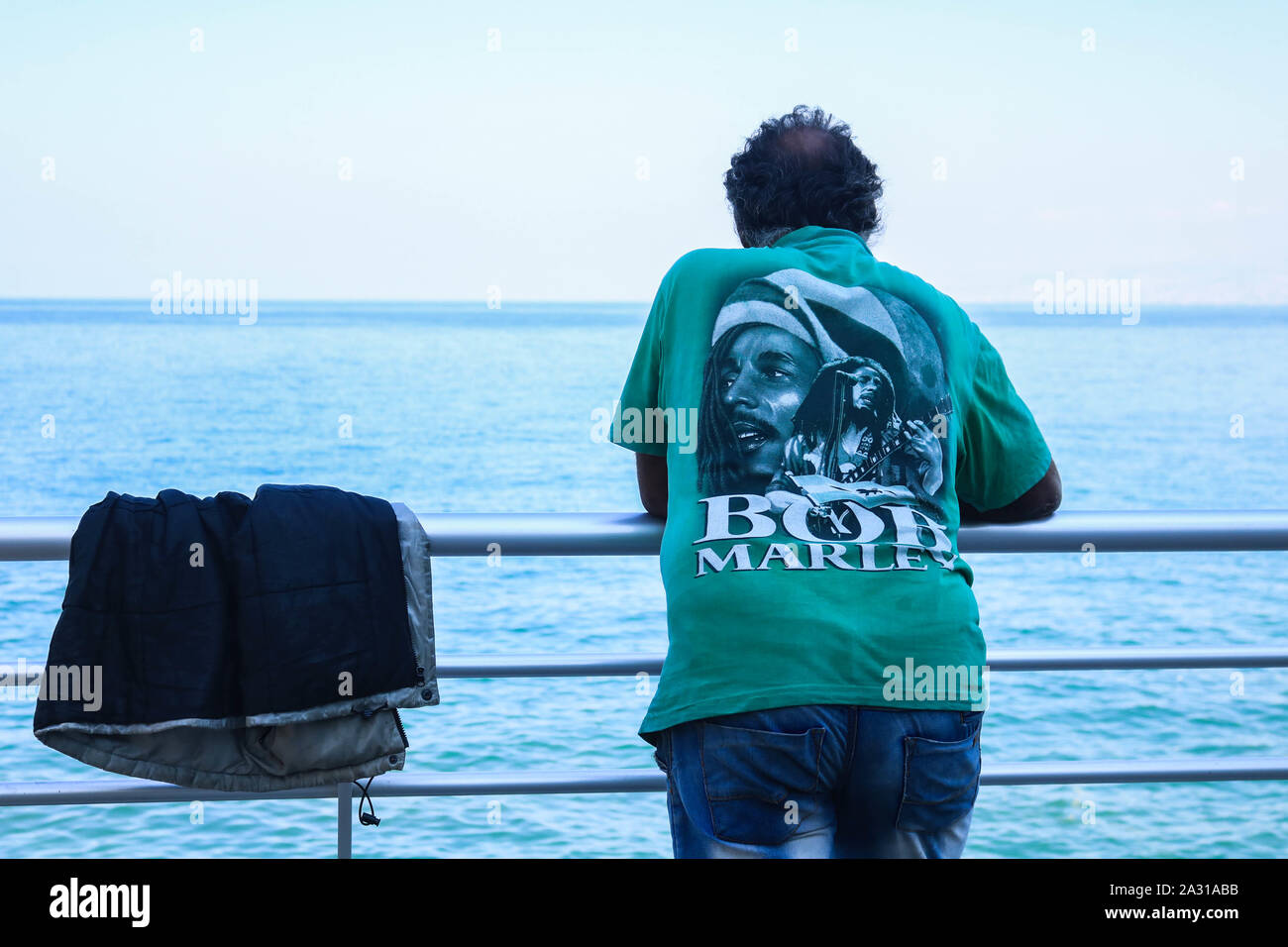 Ein Mann mit einem Bob Marley t-shirt lehnte sich an die Balustrade auf Beirut Promenade direkt am Meer an einem heißen Tag in Beirut mit überdurchschnittlichen Temperaturen Stockfoto