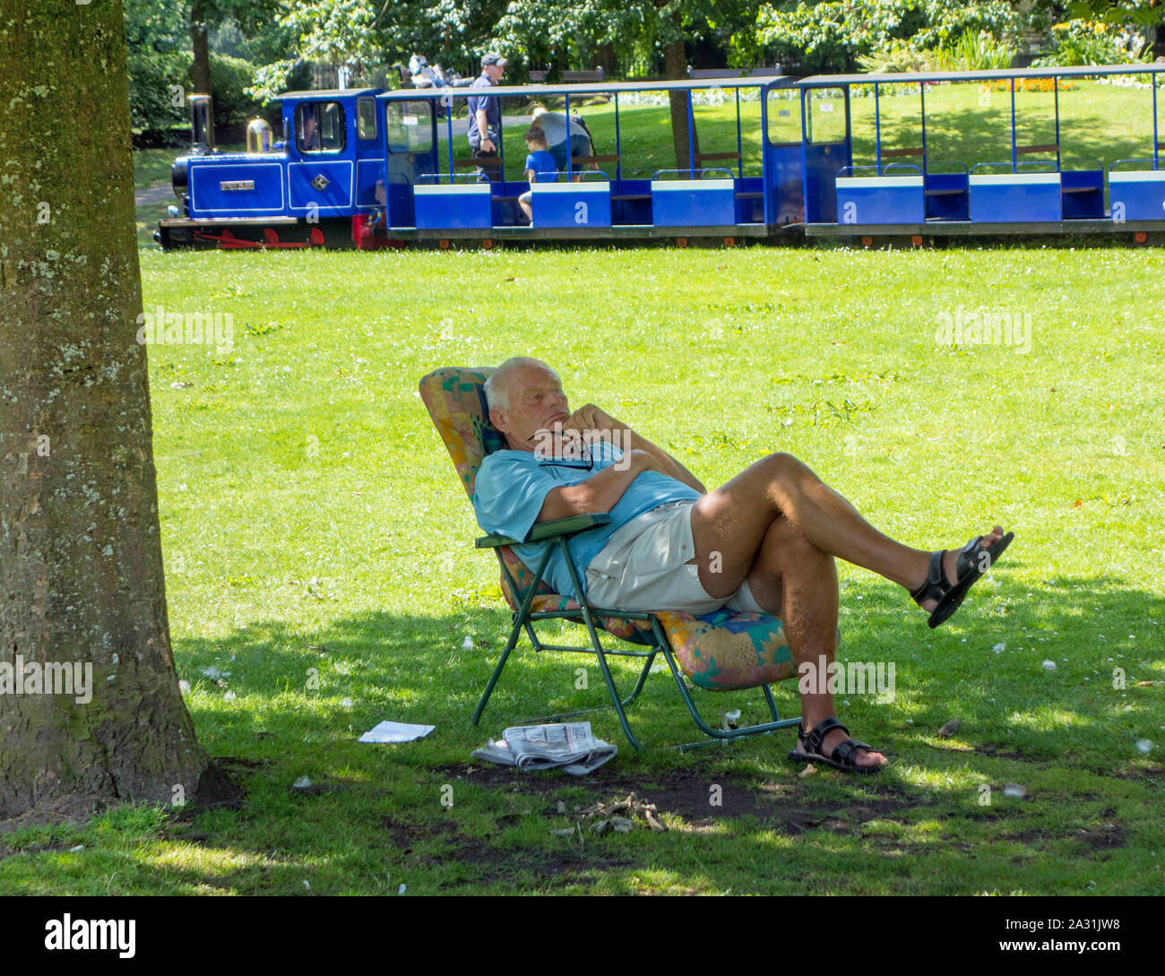 Mann sitzt im Liegestuhl entspannen am heißesten Tag des Jahres 2019 in der Pavilion Gardens im Peak District der Stadt von Buxton Stockfoto