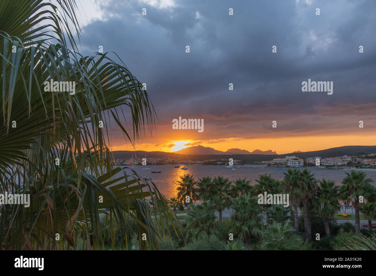 Panoramablick Sonnenuntergang gegen Berge und Himmel mit Wolken. Palmen im Vordergrund. Stockfoto