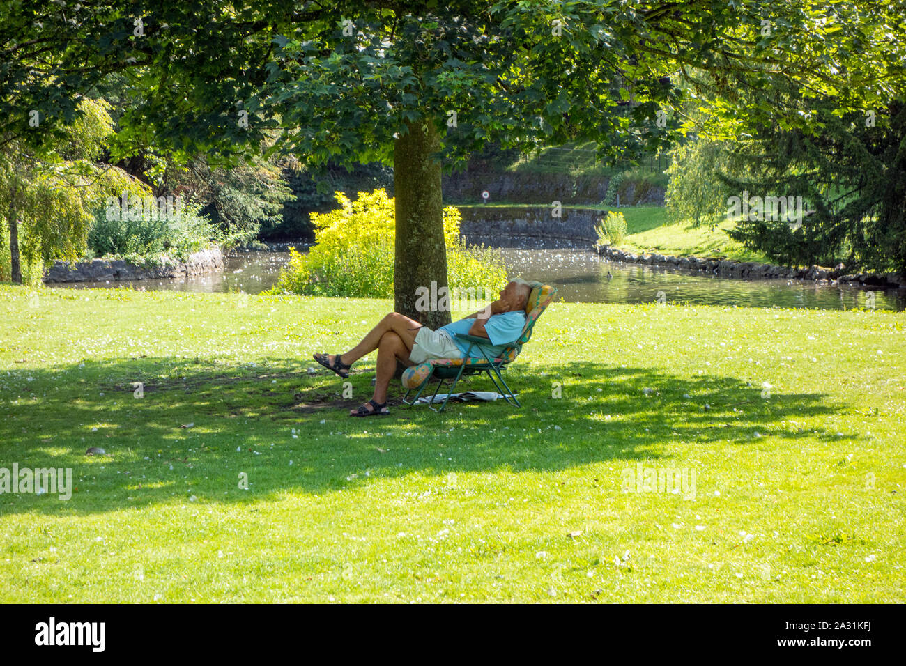 Mann sitzt in einem Liegestuhl schlafend am heißesten Tag des Jahres 2019 in der Pavilion Gardens im Peak District der Stadt von Buxton Stockfoto