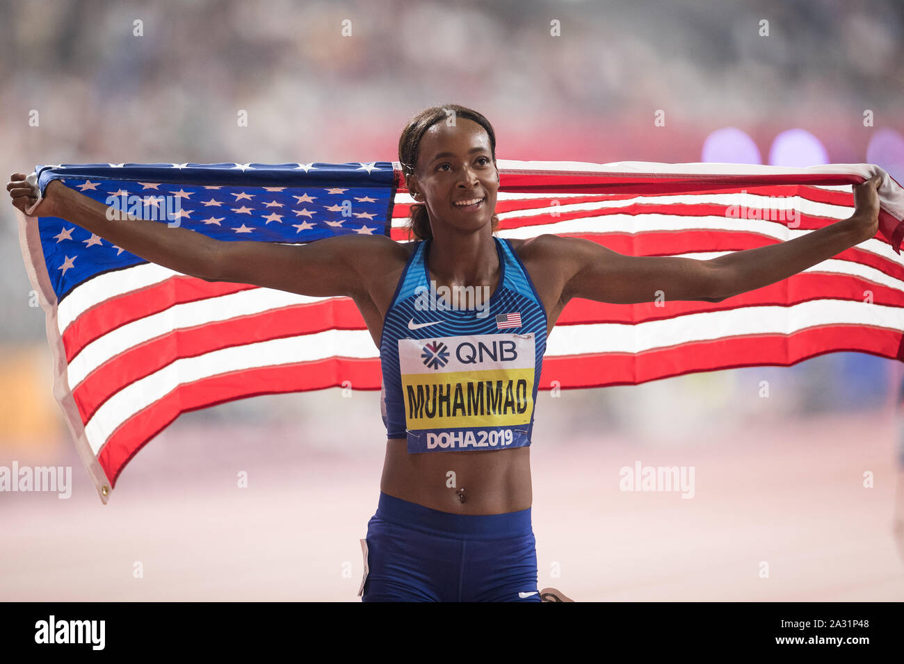 Doha, Katar. 04 Okt, 2019. IAAF Leichtathletik Weltmeisterschaft an Khalifa International Stadion: 400 m Hürden, Frauen, endgültig. Delila Muhammad aus den USA jubelt nach dem Sieg mit einer US-Flagge. Sie führt einen Weltrekord mit 56.16 Sekunden. Credit: Oliver Weiken/dpa/Alamy leben Nachrichten Stockfoto