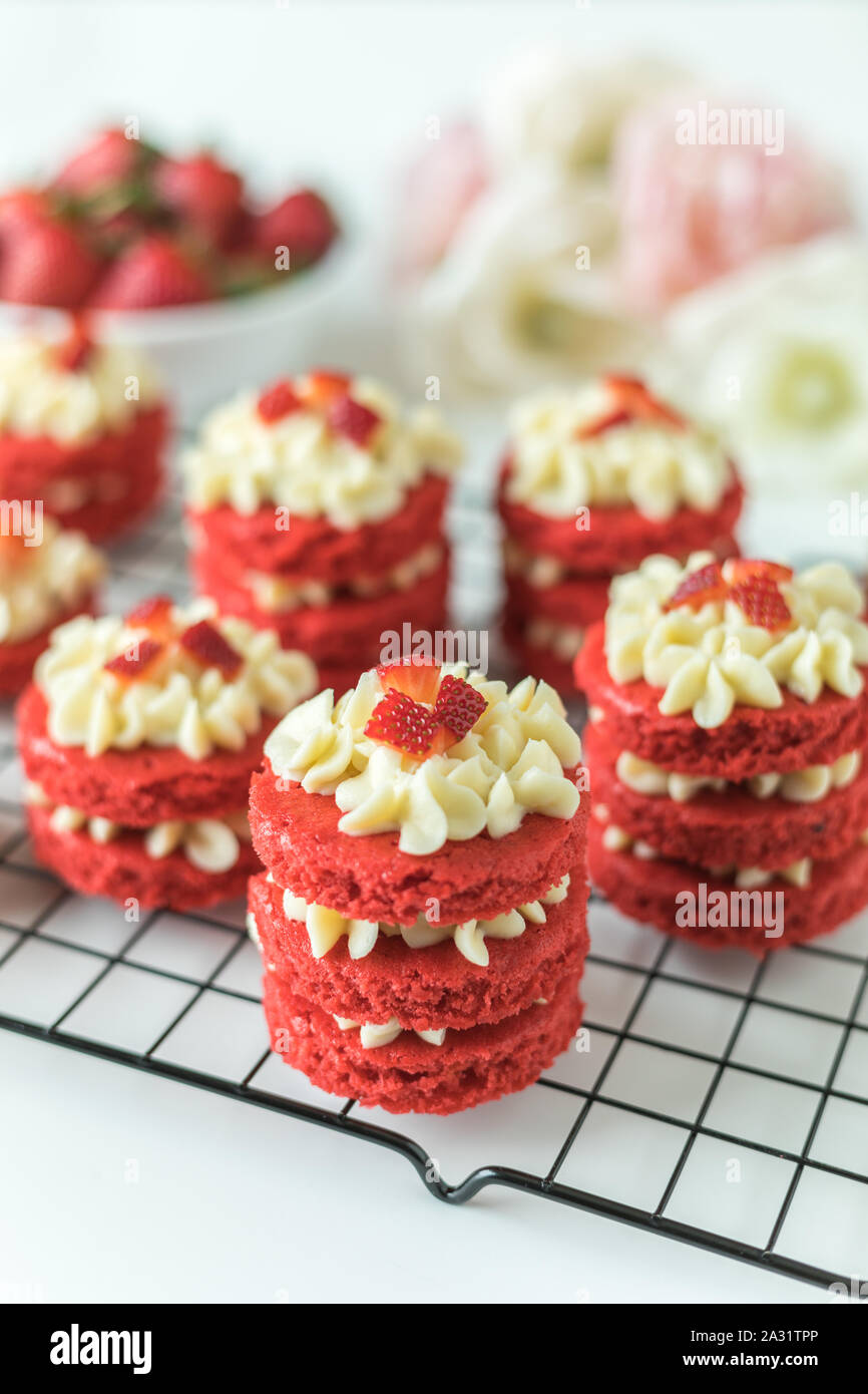 Miniatur Red Velvet Kuchen mit Cream Cheese frosting und frische Erdbeer Topping auf eine Kühlung Rack Stockfoto