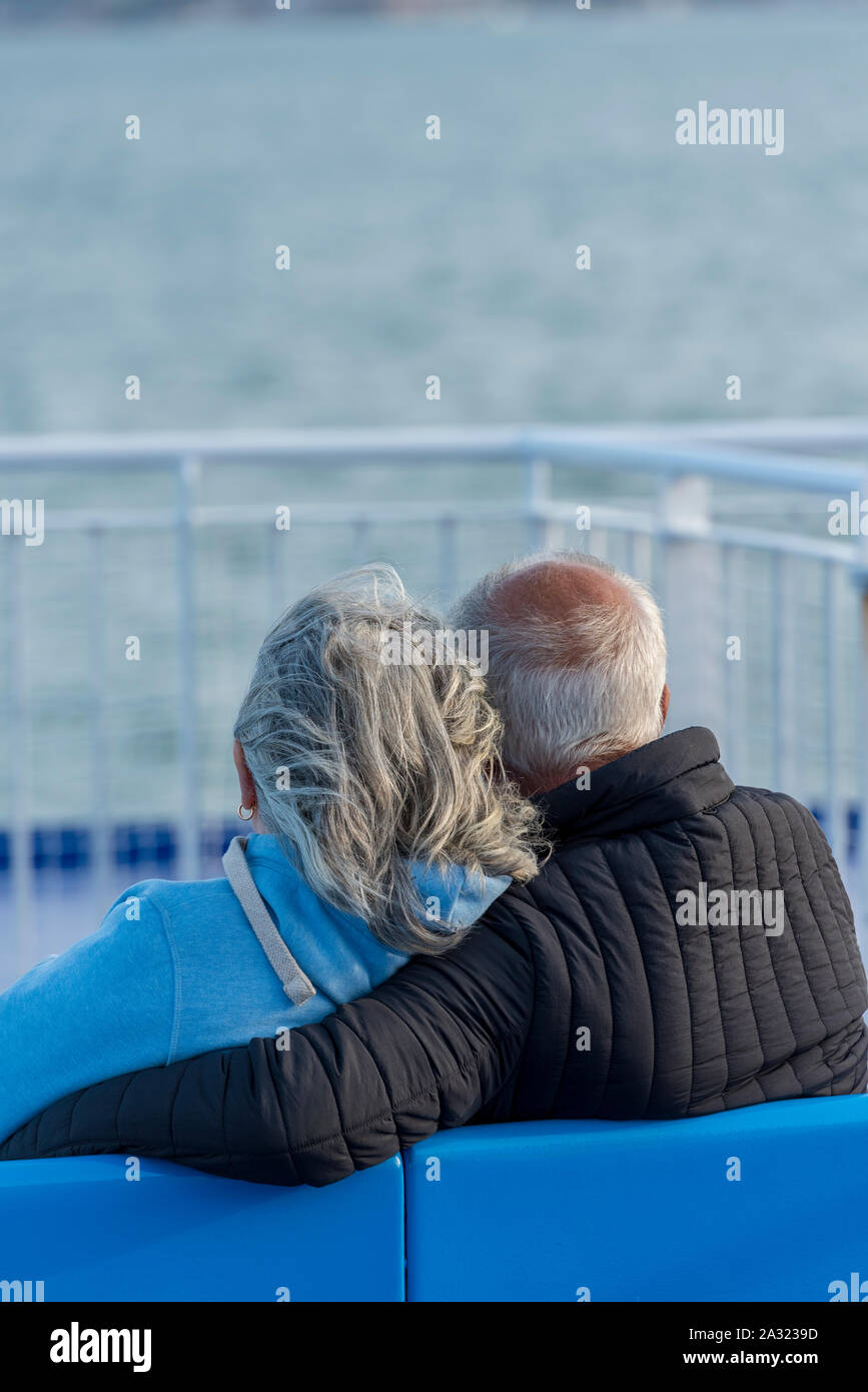 Ein älteres oder älteres Ehepaar, das im Urlaub mit grauen Haaren eng auf einem Boot kuschelt. Stockfoto