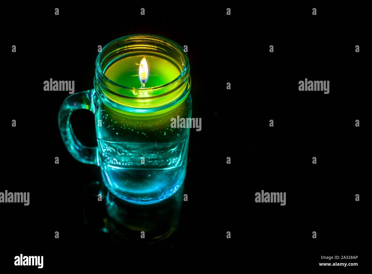 Ein wunderschönes und farbenfrohes brennende Kerze mit Reflexion auf einem dunklen Hintergrund isoliert Stockfoto