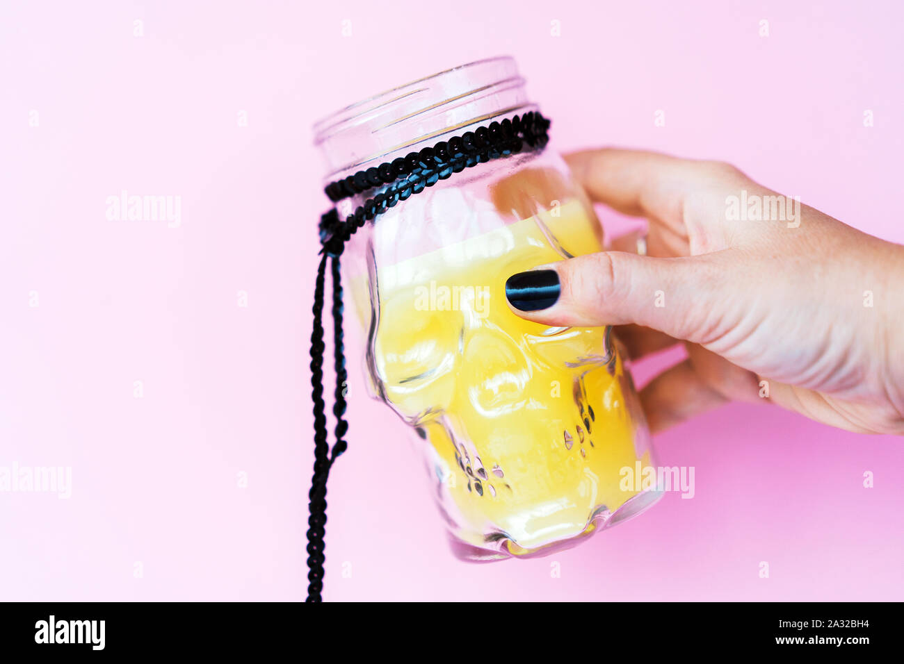 Kreative Halloween Tag Zusammensetzung. Urlaub Kerze Totenkopf Glas in der Hand Stockfoto