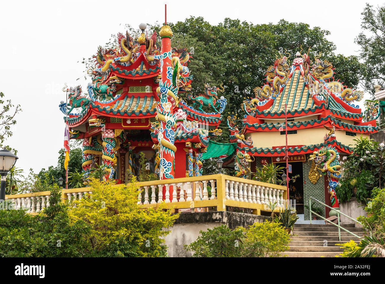 Si Racha, Thailand - 16. März 2019: Rot, Gold, Gelb Wat Koh Loy buddhistischen Heiligtümer auf dem Hügel von Ko Loi Insel mit grün Laub und unter Silber sk Stockfoto
