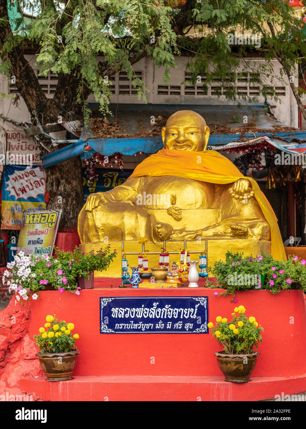 Si Racha, Thailand - 16. März 2019: Goldene beleibt sitzender Buddha Statue auf rotem Sockel unten von Wat Koh Loy buddhistischen Heiligtümer auf dem Hügel von Ko Loi I Stockfoto