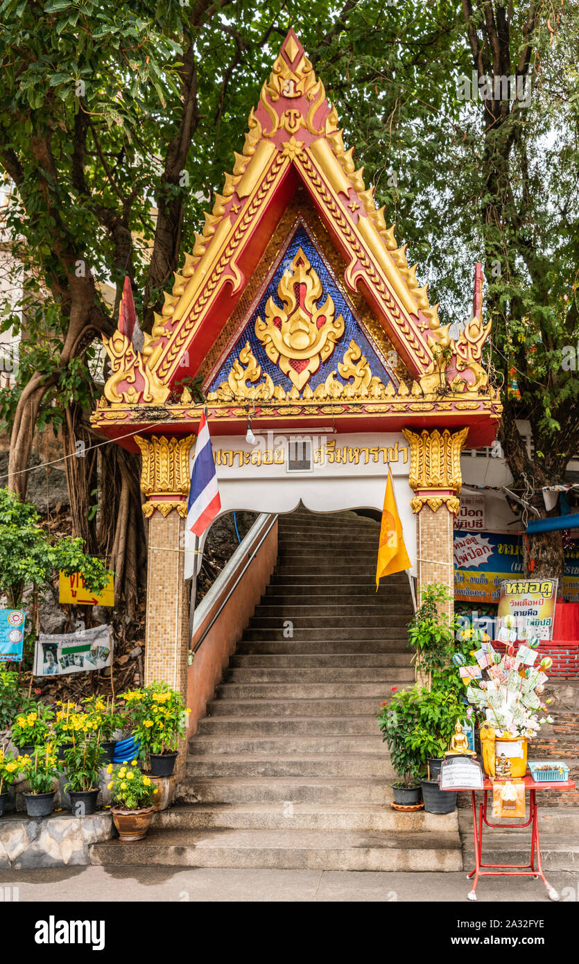 Si Racha, Thailand - 16. März 2019: Rot, Blau, Gold Gate auf der Treppe zu Wat Koh Loy buddhistischen Heiligtümer auf dem Hügel von Ko Loi Insel mit grün Laub. Stockfoto