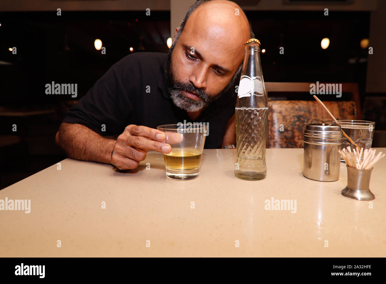 Ein Model posiert wie ein betrunkener Mann in seinem glaas von trinken Alkohol Stockfoto