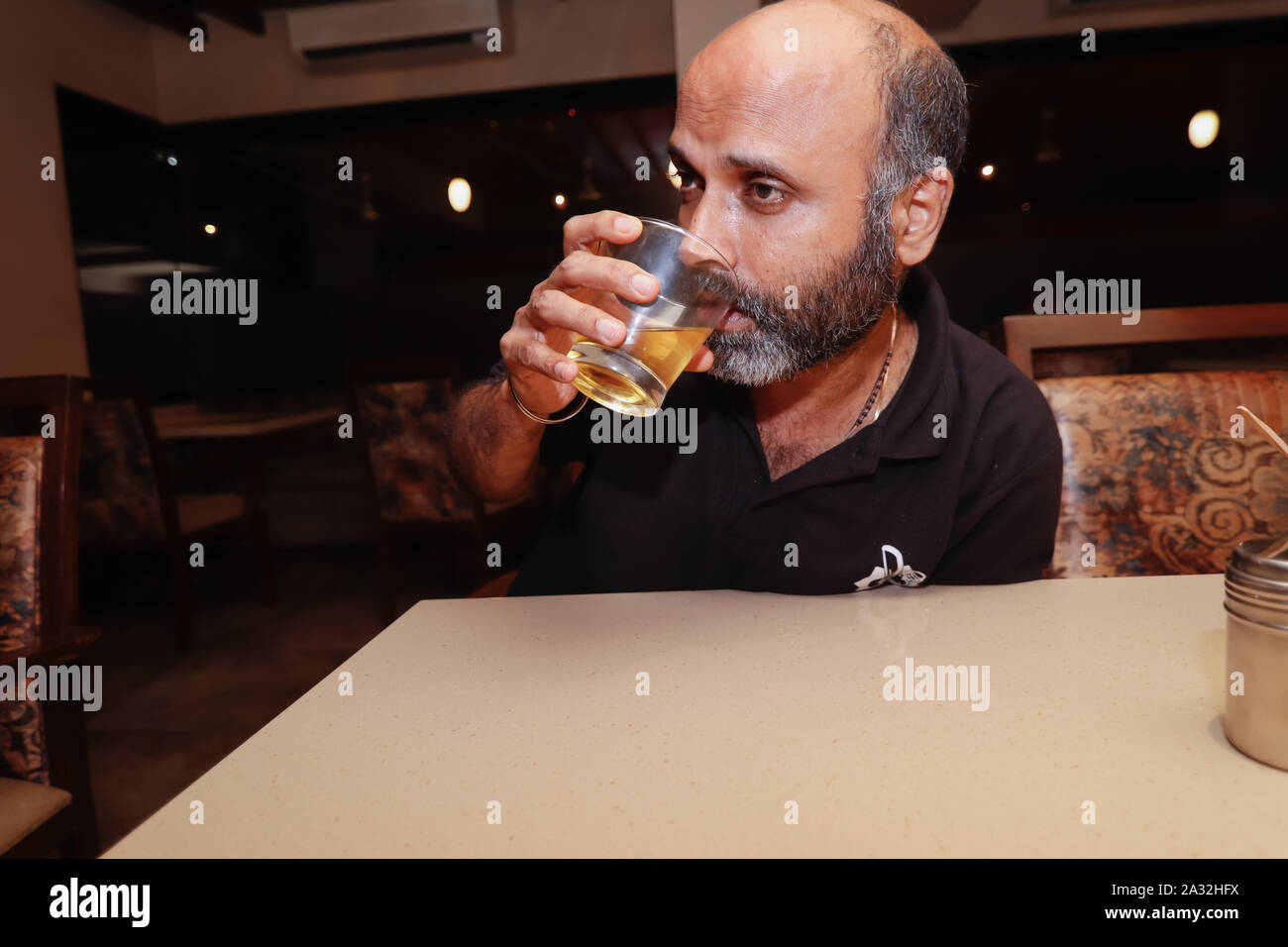 Ein Model posiert wie ein betrunkener Mann in seinem glaas von trinken Alkohol Stockfoto