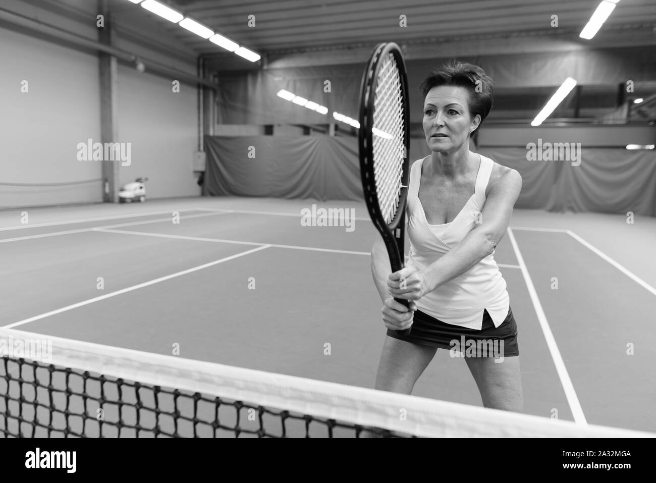 Reife Frau, schön spielen Tennis auf Innen- hof Stockfoto