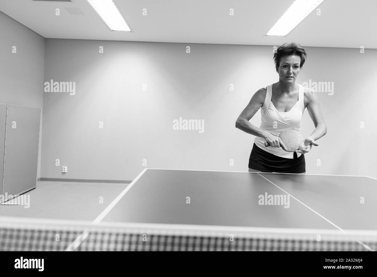 Reife Frau, schön spielen Tischtennis im Innenbereich Stockfoto