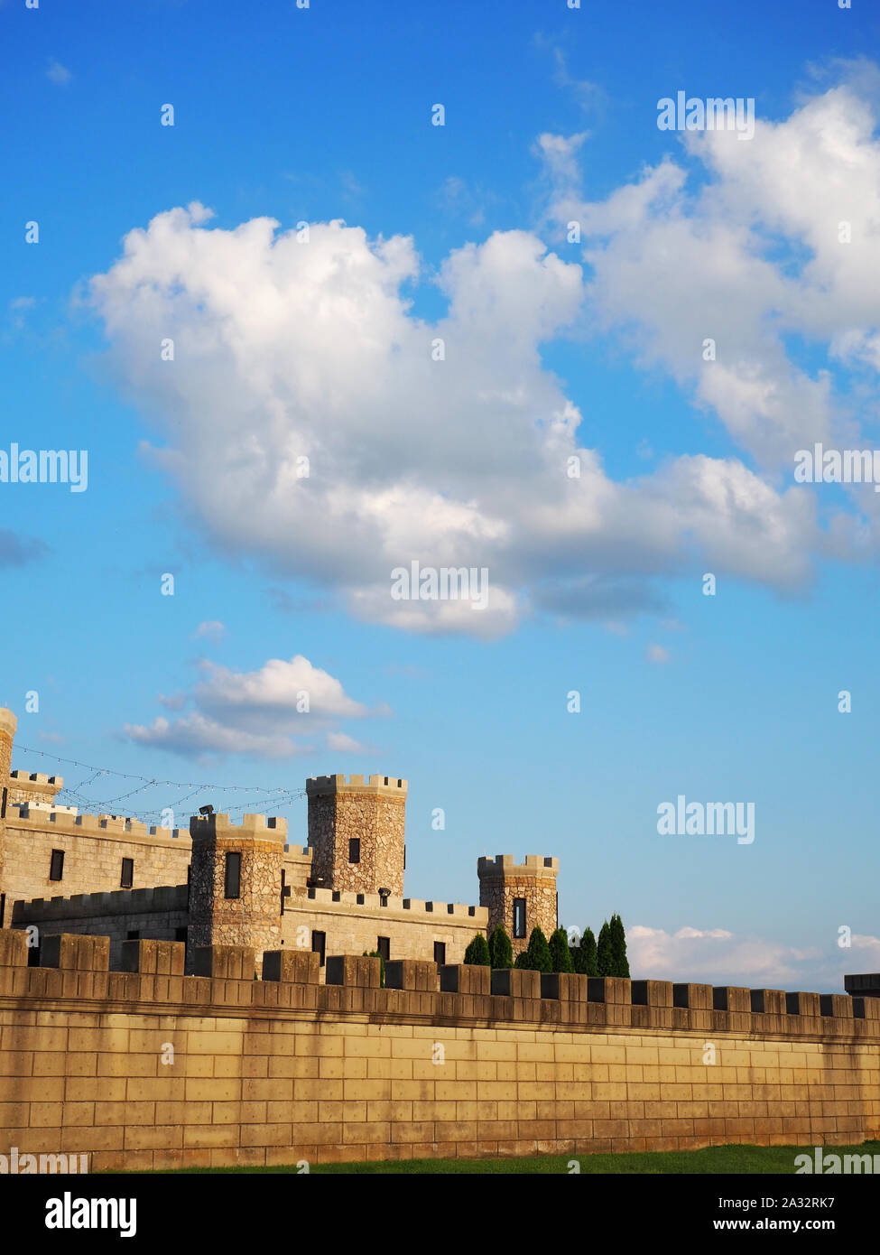 Eine lange Mauer mit Zinnen vor einem mittelalterlichen Stil steinerne Burg bietet Schutz zu den wichtigsten Teil der Burg, bekannt als das halten. Stockfoto