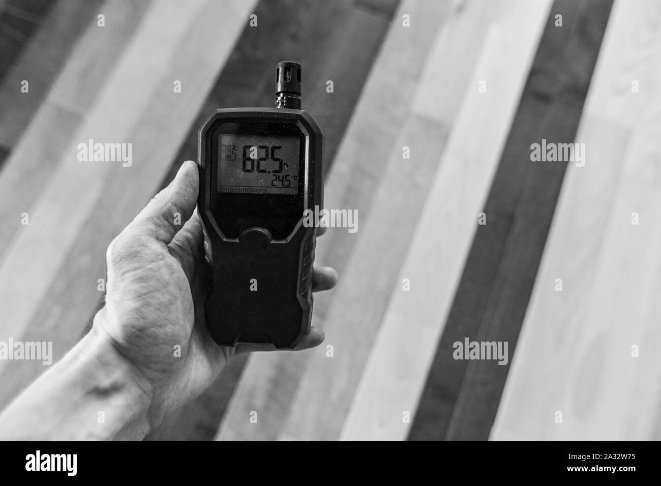 Eine Nahaufnahme und monochrom Blick auf eine Person, die ein Handheld-digitales Gerät, Kontrolle der Luftqualität innerhalb einer inländischen Wohnung während eines Lebens Qualität prüfen. Stockfoto