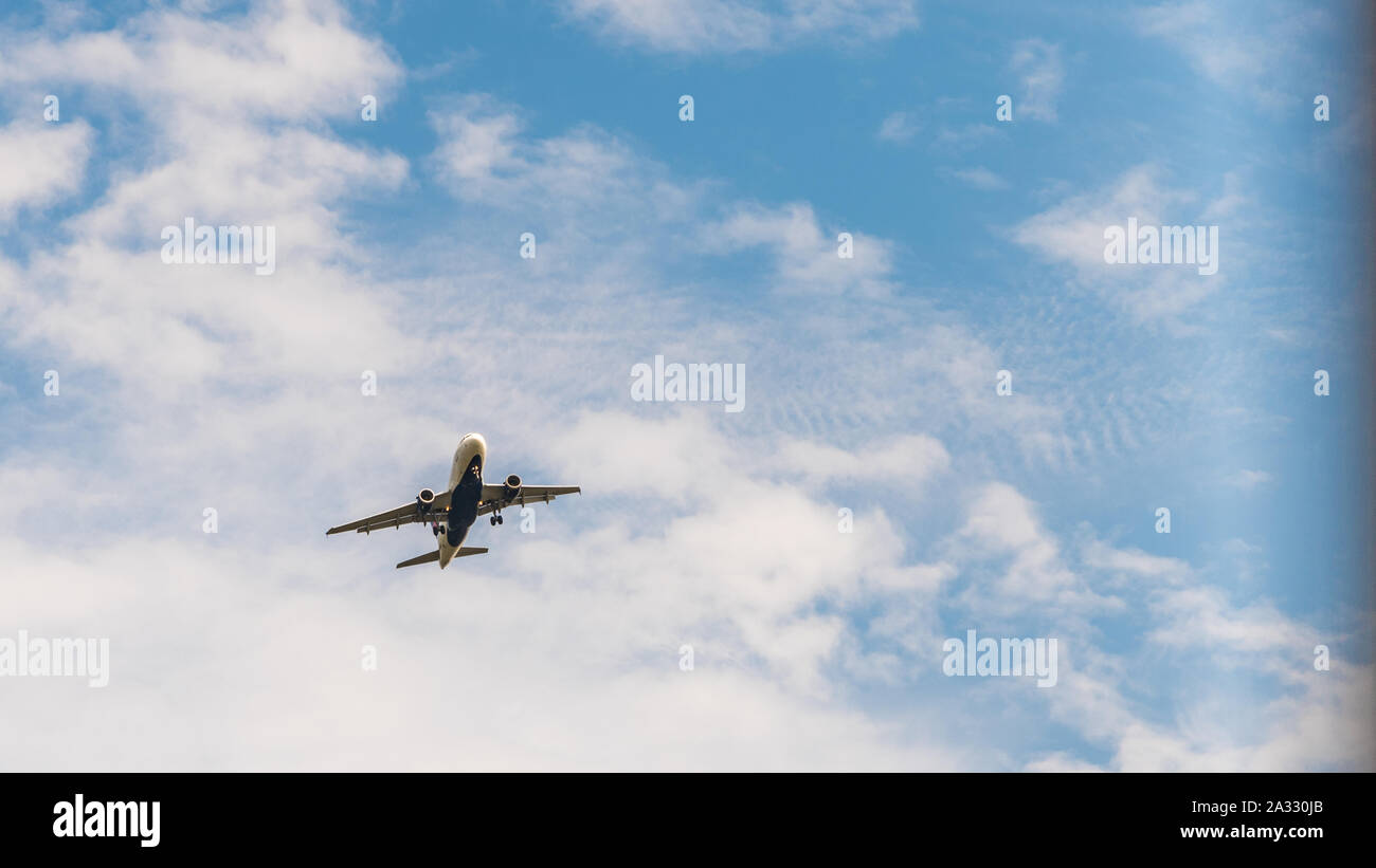 Jetliner in geringer Höhe mit Wolken und blauer Himmel im Hintergrund Stockfoto