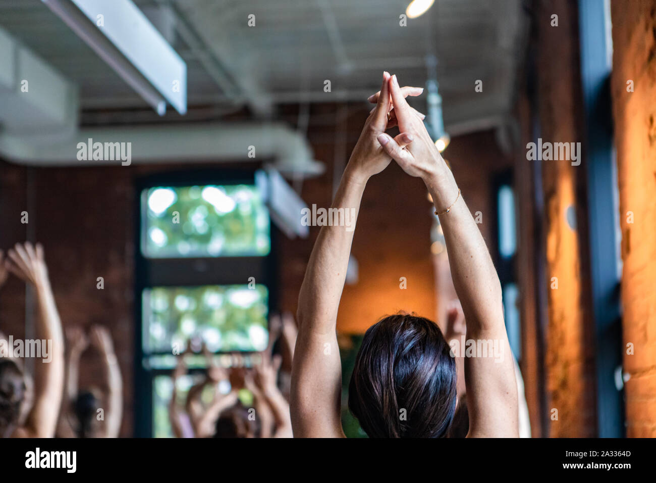 Eine junge Frau ist in der Nähe gesehen, und von hinten, als sie ihre Arme zur Decke gestreckt. Spirituelle Übungen während 108 Sonne begrüßt. Stockfoto