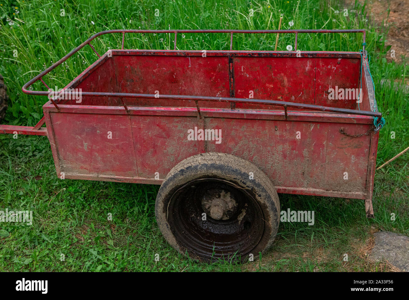 Eine alte rostige und Dreck bedeckt Anhänger ist in der Nähe ein Campingplatz gesehen. Mit schlammigen Reifen und splatter Markierungen über den roten Rahmen. Stockfoto