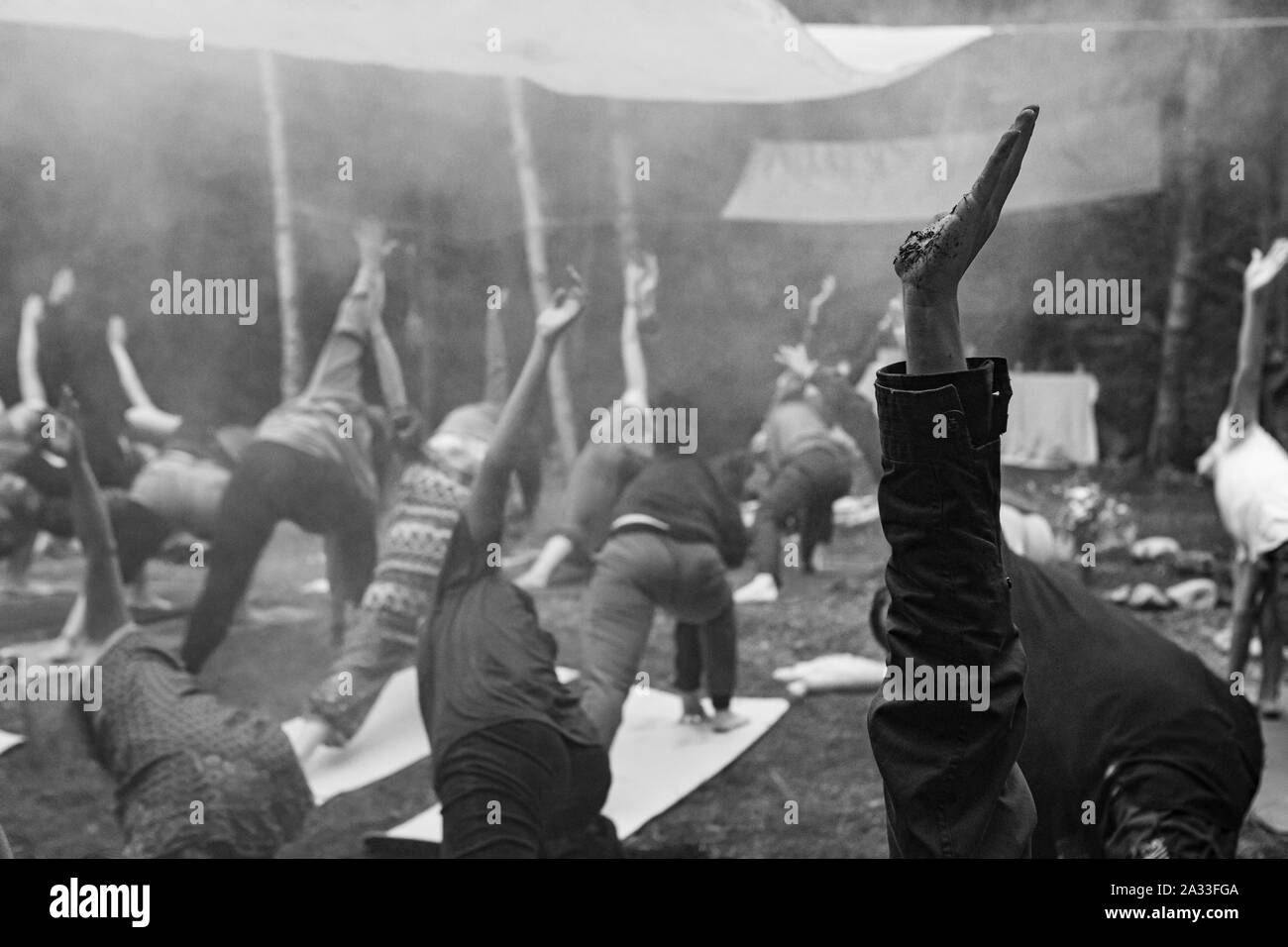 Eine atmosphärische Schwarz-Weiß-Ansicht auf eine multiethnische Gruppe von vernünftigen Menschen üben Yoga Posen in Wäldern während einer schamanischen Rückzug. Stockfoto