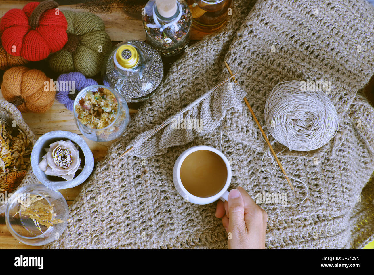 Top-Ansicht Frau Hand halten Morgen Kaffeetasse auf Herbst Hintergrund mit Dekor saisonale Ornament Tisch für Heimdekor als Kürbis, Burlap Gericht Tuch Stockfoto