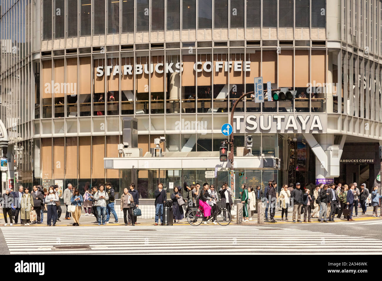 9. April 2019: Tokyo, Japan - Masse von Menschen warten auf der Straße bei Shibuya Crossing zu überschreiten, mit Starbucks Kaffee hinter Ihnen. Stockfoto