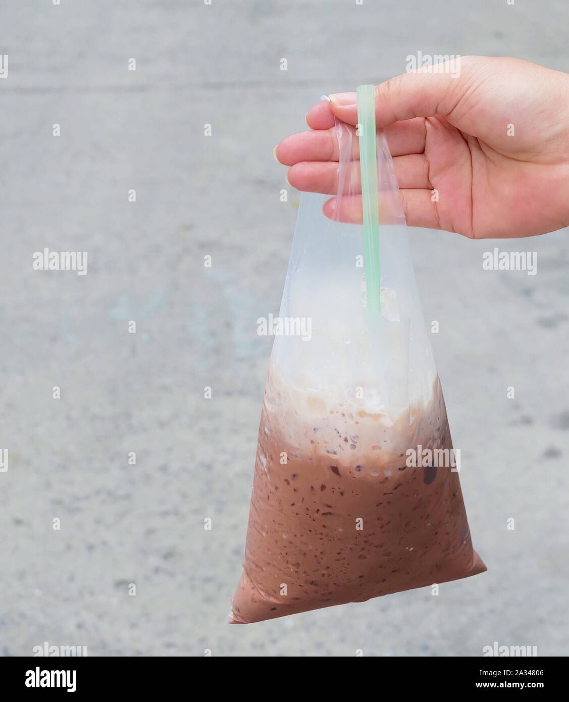 Trinken, Trinken, Hand Hodling thai Eiskaffee oder Eisschokolade im Beutel. Stockfoto