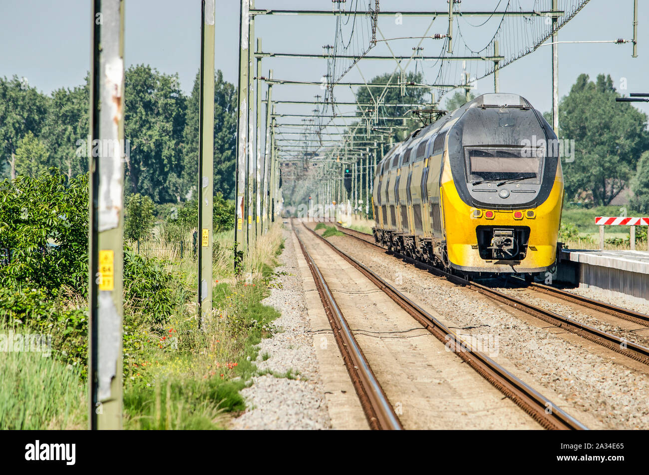 Bruinisse, Niederlande, 29. Juni 2019: teleobjektiv Bild einen gelben Niederländische Bahn Intercity Zug verlassen Sie den Bahnhof in Richtung Middelburg eine Stockfoto