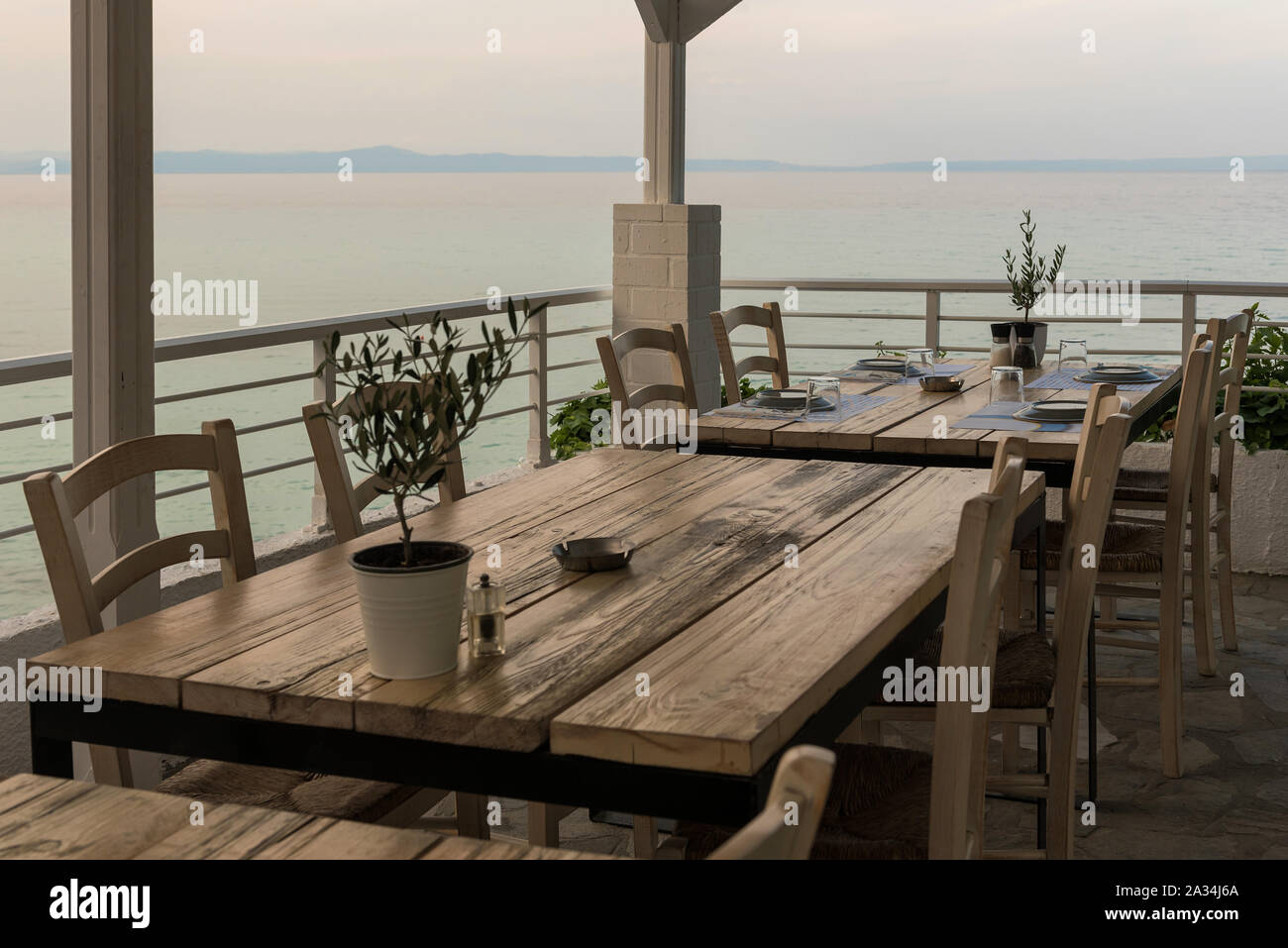 Mediterranes Restaurant Holztisch mit Olivenbaum, Setup, Salz und Pfeffer und Meerblick Stockfoto