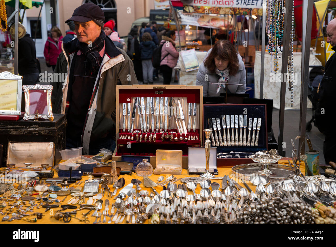 Standbesitzer/Halter mit einer Tabelle der sammelbaren Besteck/Messer, Gabeln usw. Am stall Sammlerstücken und Antiquitäten Markt, Greenwich Market zu Weihnachten. London. Großbritannien (105) Stockfoto