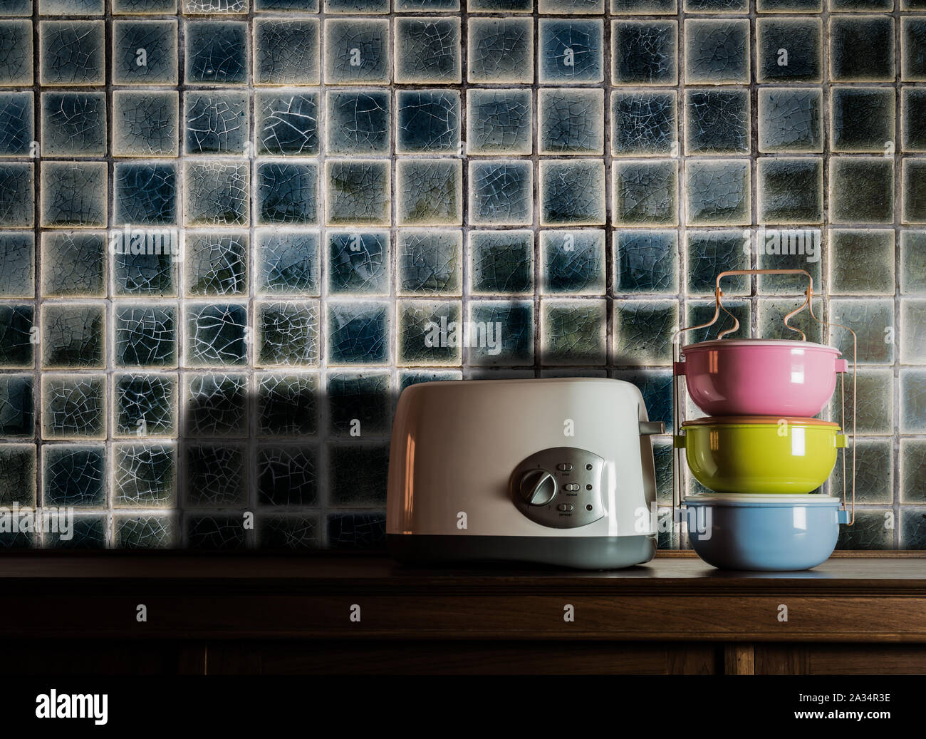Bunte tiffin Träger und Toaster auf Holz Schrank in der Küche Zimmer gegen warmes Licht Stockfoto