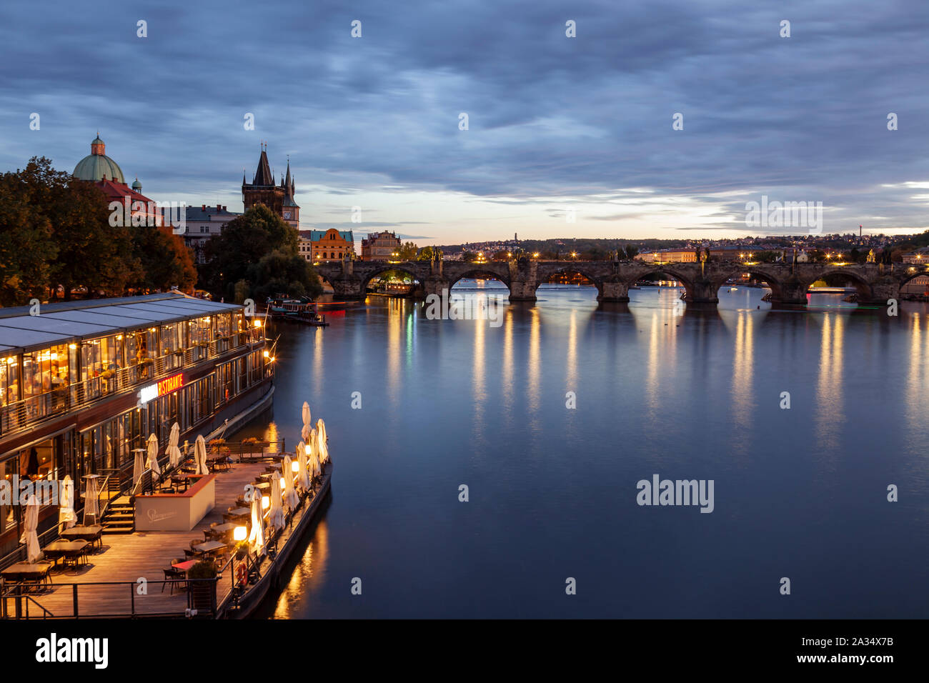 Nacht fällt an der Moldau in Prag, Tschechien. Charles Bridge in der Ferne. Stockfoto