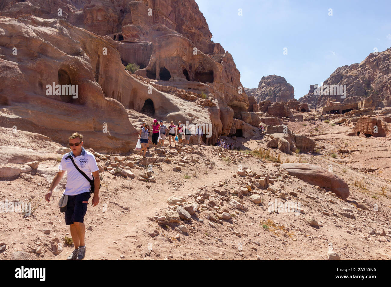 Petra, Jordanien - Sept 21, 2013: Sportliche junge Touristen zu Fuß entlang der alten Grab Häuser, die in den Bergen von Petra, Jordanien geschnitzt werden Stockfoto