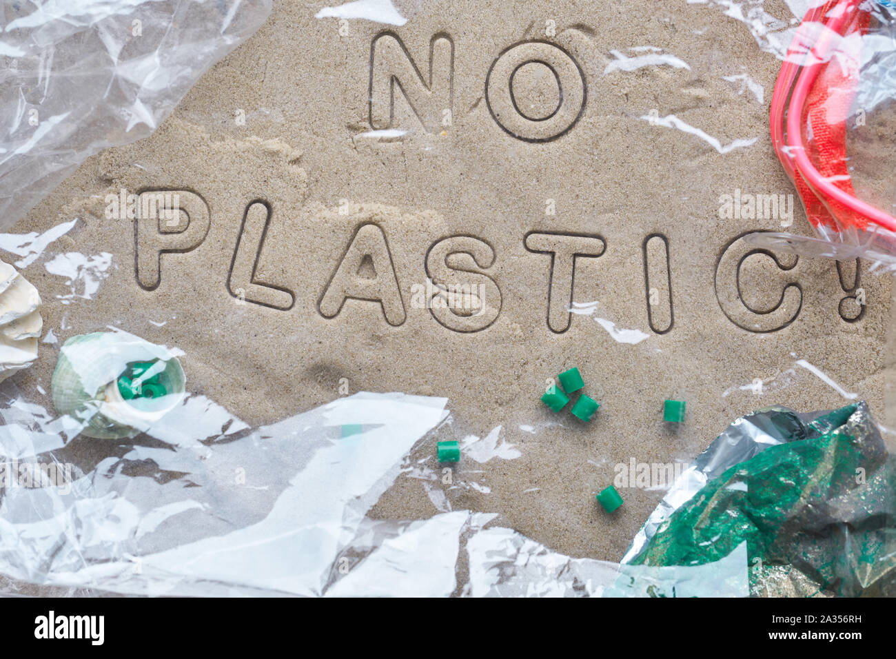 Kein Kunststoff text auf Sand mit verschiedenen Ablagerungen gerahmt und mit Klarsichtfolie abgedeckt. Die Verschmutzung ist schädlich für die marine Leben. Umweltkonzept. Verbot Stockfoto