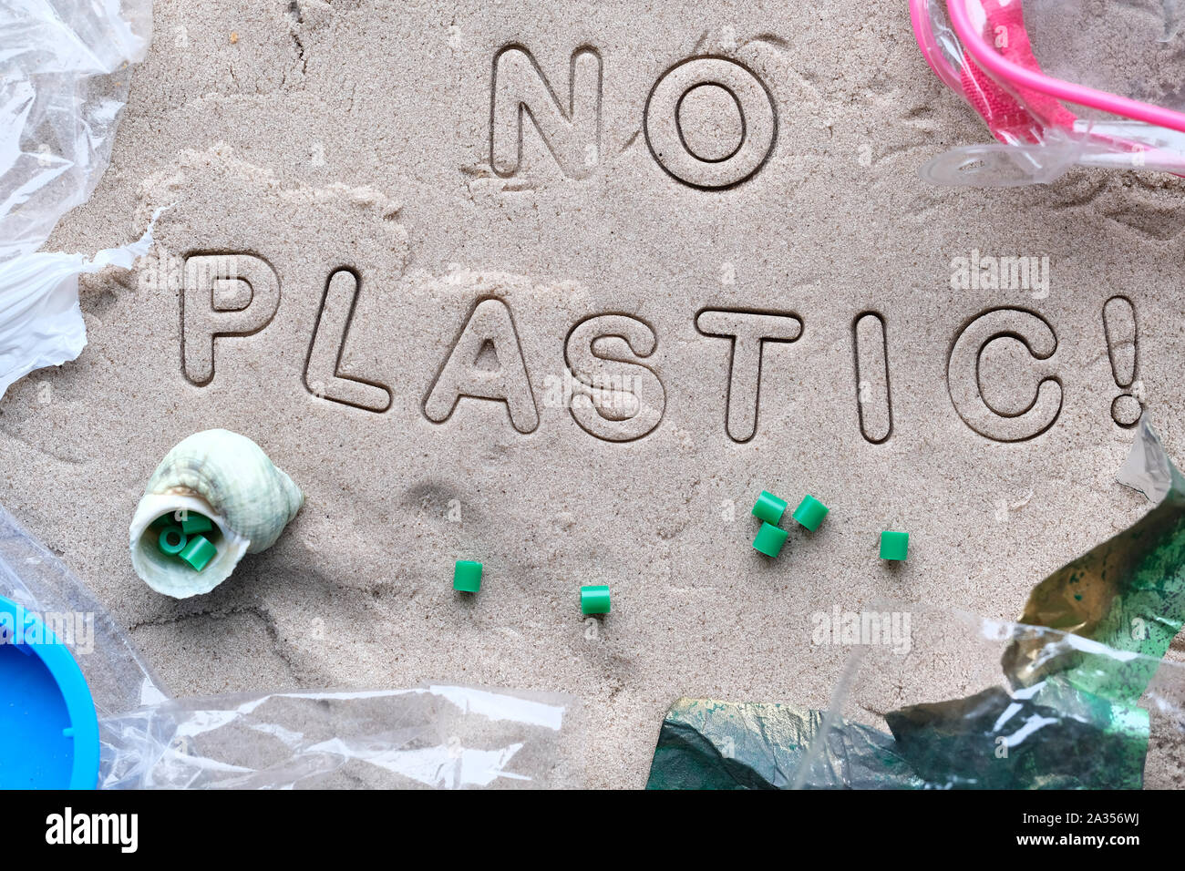 Kein Kunststoff text auf Sand mit verschiedenen Ablagerungen gerahmt und mit Klarsichtfolie abgedeckt. Die Verschmutzung ist schädlich für die marine Leben. Umweltkonzept. Verbot Stockfoto